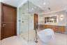 Glass-enclosed walk-in shower with mosaic tile surround and rainfall showerhead, freestanding soaking tub with floor-mounted faucet, wall-mounted wood