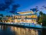 Multi-story modern residence featuring stone veneer siding, expansive glass sliders, multiple tiered balconies with glass railings, a swimming pool, a