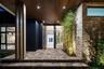 Covered entryway featuring a wood-panelled ceiling, stacked stone accent wall, multi-tiered stone paver stairs, vertical column detailing, and recesse
