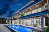 Contemporary multi-level exterior featuring stacked stone masonry, recessed soffit lighting, glass panel balcony railings, and a heated pool with an i
