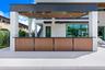 Outdoor kitchen featuring a wood-panel base, dark stone countertop, built-in sink, recessed ceiling lighting, and a metal-framed roof structure