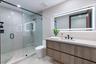 Modern bathroom featuring a wood-finish floating vanity with a white countertop, walk-in glass-enclosed shower with matte black fixtures, and a large 