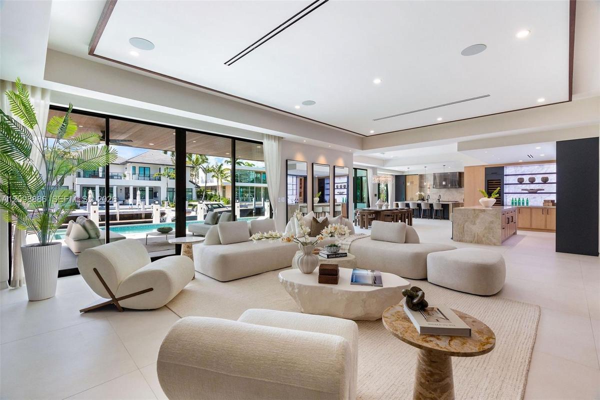 Open-concept living area featuring large-format tile flooring, a recessed tray ceiling with integrated lighting, expansive floor-to-ceiling glass slid