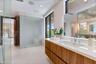 Built-in wood-paneled sauna featuring a glass-door entrance, accompanied by a walk-in shower with a mosaic-tiled accent wall, glass enclosure, transom