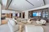Open-concept living space featuring a recessed tray ceiling, custom built-in cabinetry with integrated display lighting, and large-format tile floorin
