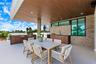 Covered outdoor living space featuring a wood-finish ceiling with recessed lighting, stone veneer wall, integrated kitchenette with stainless steel gr