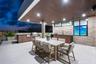Covered outdoor terrace featuring a built-in stainless steel grill, stone veneer accent wall, recessed lighting, and expansive wood-finish ceiling sof