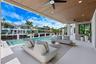 Covered patio featuring a wood-plank ceiling, recessed lighting, and dual ceiling fans, complete with a stone-accented wall and a custom pool borderin