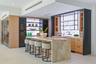 Kitchen featuring a waterfall-edge stone island, built-in dual wine refrigeration, stone slab backsplash, recessed ceiling lighting, and custom cabine