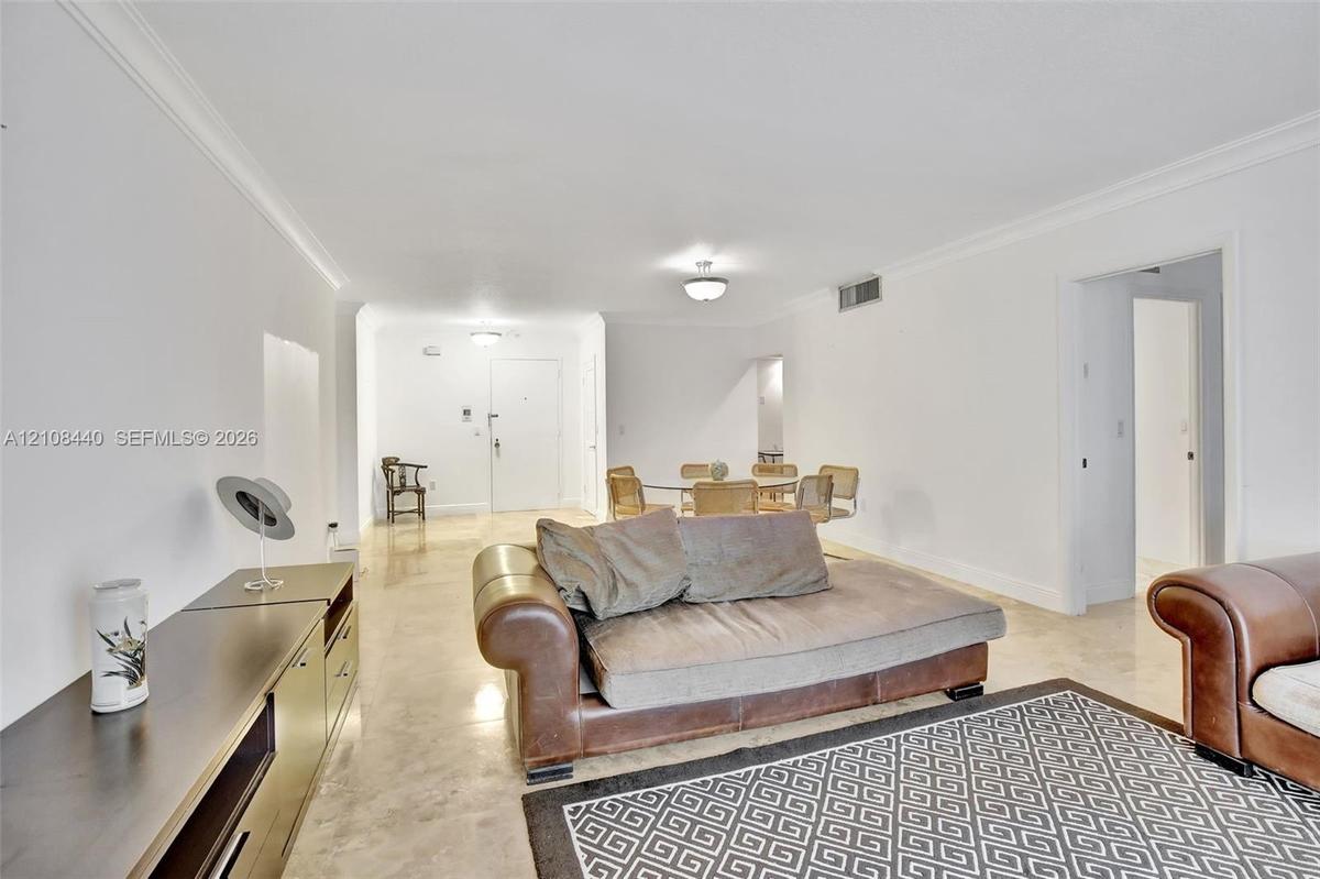 Open-concept interior featuring smooth-finish tile flooring, recessed crown molding, and neutral wall tones