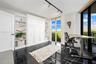 Polished black tile flooring, floor-to-ceiling windows, built-in cabinetry with integrated shelving, and adjustable track lighting