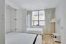 Built-in white cabinetry, natural stone flooring, and large window with dark-frame panes