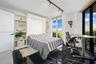 Built-in floor-to-ceiling white shelving, integrated wall bed system, black tile flooring with veining, track lighting, and full-height windows