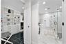 Walk-in closet featuring white built-in shelving and drawer cabinetry, complemented by high-gloss dark stone-finish flooring
