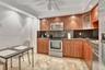 Kitchen featuring natural wood cabinetry, stone countertops, stainless steel appliances, and tile flooring with recessed lighting