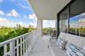 Covered balcony featuring large-format porcelain tile flooring, white metal railing, and floor-to-ceiling glass sliding doors