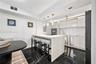Kitchen featuring an island with a stone-finish waterfall edge, high-gloss cabinetry, stainless steel appliances, pendant lighting, and polished stone