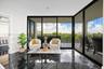 Polished dark stone tile flooring, expansive floor-to-ceiling glass walls, and a private outdoor balcony with metal railing