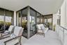 Covered balcony featuring oversized tile flooring, full-height glass-paneled sliding doors, and a metal railing