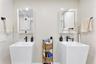 Dual pedestal sinks featuring rectangular basins and matte black faucets, paired with mirrored medicine cabinets and matte black hardware
