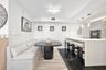 Kitchen featuring a stone-surface waterfall island, black tile flooring with white veining, built-in dual ovens, and trio of pendant lights
