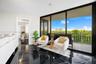 Polished black flooring with white veining, expansive floor-to-ceiling sliding glass doors, and a private balcony with metal railing