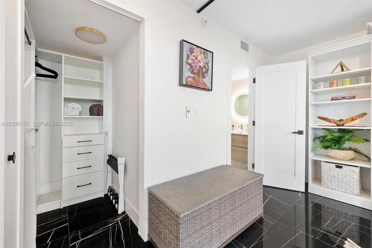 Custom walk-in closet featuring white built-in shelving, integrated dresser drawers with matte black hardware, floor-to-ceiling cabinetry, and polishe