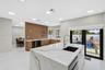 Kitchen featuring an island with a stone-finish countertop, undermount sink, matte black gooseneck faucet, wood-finish cabinetry, and recessed lightin