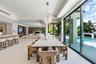 Open-concept interior featuring large-format tile flooring, a statement crystal chandelier, built-in cabinetry, a fireplace with stone surround, and f