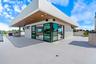 Expansive rooftop terrace featuring large-format tile flooring, a cantilevered roof overhang with wood-finish soffits, recessed lighting, and floor-to