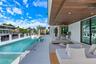 Covered patio featuring a wood-plank ceiling with recessed lighting, integrated lap pool with tiled interior, stacked stone wall accent, and expansive