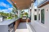 Covered outdoor kitchen featuring wood-finish cabinetry, stone countertops, a built-in stainless steel grill, and recessed ceiling lighting