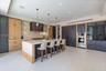 Kitchen featuring custom two-tone cabinetry, expansive stone-topped central island, built-in stainless steel double ovens, integrated refrigerator, an