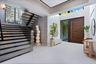 Grand foyer featuring large-format tile flooring, a custom wood-finished entry door with a vertical pull handle, a dramatic staircase with glass raili