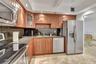 Kitchen featuring wood cabinetry, stone countertops, dark stone backsplash, stainless steel appliances, and recessed lighting