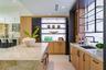 Custom kitchen featuring a large stone-surfaced island, light wood cabinetry, integrated wine refrigeration, an illuminated stone backsplash, and matt
