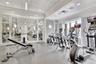 Fitness space featuring floor-to-ceiling mirrors, a coffered ceiling with recessed lighting, wall-mounted sconces, and impact-resistant rubber floorin