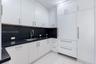 Kitchen featuring flat-panel white cabinetry, contrasting dark stone countertops, integrated panel-ready refrigerator, stainless steel undermount sink
