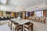 Gourmet kitchen featuring quartz countertops, wood-finish cabinetry, a geometric crystal chandelier, integrated wine refrigeration, and large-format t