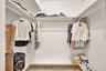 Walk-in closet featuring tiered shelving, integrated clothing rods, and tile flooring