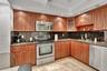 Kitchen featuring wood cabinetry, stainless steel appliances, dark stone-finish countertops, recessed lighting, and tile flooring