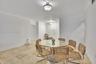 Neutral-toned natural stone flooring, crisp white walls, crown molding, and dual semi-flush mount light fixtures