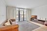 Living space featuring full-height floor-to-ceiling glass sliding doors, neutral stone-finish flooring, and crown molding