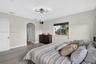 Wood-finish flooring, geometric ceiling lighting, arched entryway, and single-hung window with dark window treatments