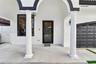 Covered entryway featuring structural columns, stucco exterior finish, full-glass front door, and paneled garage door
