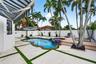 In-ground pool with integrated spa, paver patio with turf detailing, retractable fabric awning, and perimeter privacy fencing