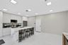 Kitchen featuring floor-to-ceiling cabinetry, a waterfall-edge island with stone-finish countertops, large-format tile flooring, and integrated square
