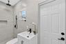 Full-height neutral wall tiling, walk-in shower with rainfall showerhead and built-in wall niche, white vanity with rectangular basin and matte black 