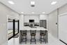 Kitchen featuring floor-to-ceiling cabinetry, a central island with a waterfall-edge countertop, stainless steel appliances, recessed lighting, and la