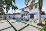 Backyard featuring an in-ground swimming pool, raised composite deck, custom concrete paver patio with turf detailing, and privacy fencing